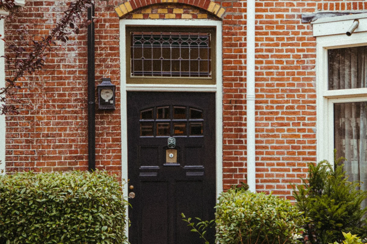 Donkere voordeur in een gevel van rode baksteen